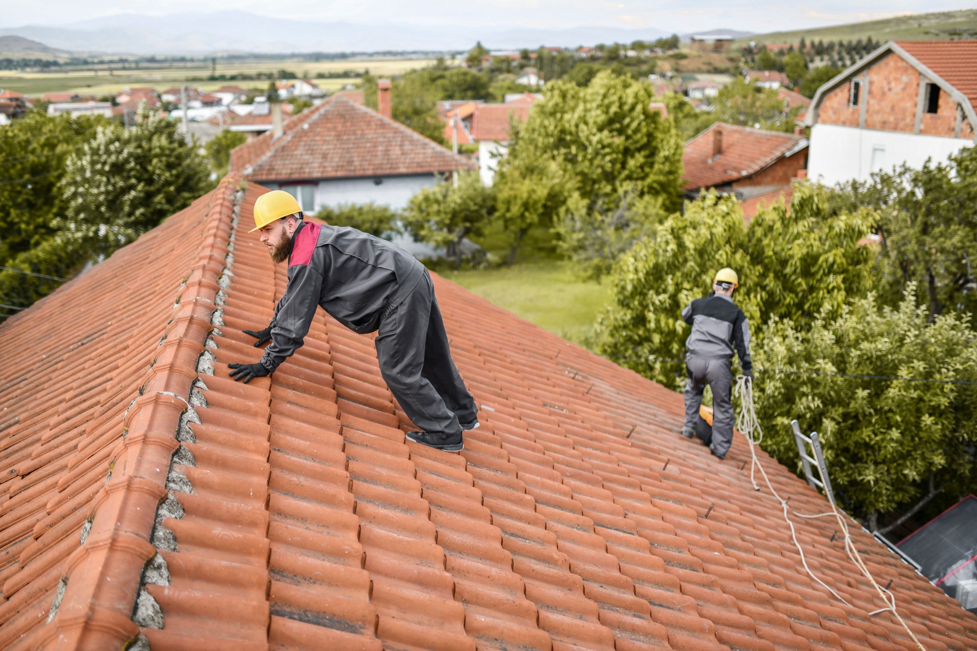 Travailleur barbu luttant pour garder l’équilibre sur le toit de la maison avant d’installer un panneau solaire